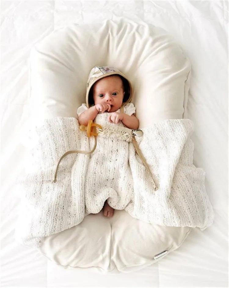 Beige portable cotton baby nest crib cushion for newborn infant sleep.