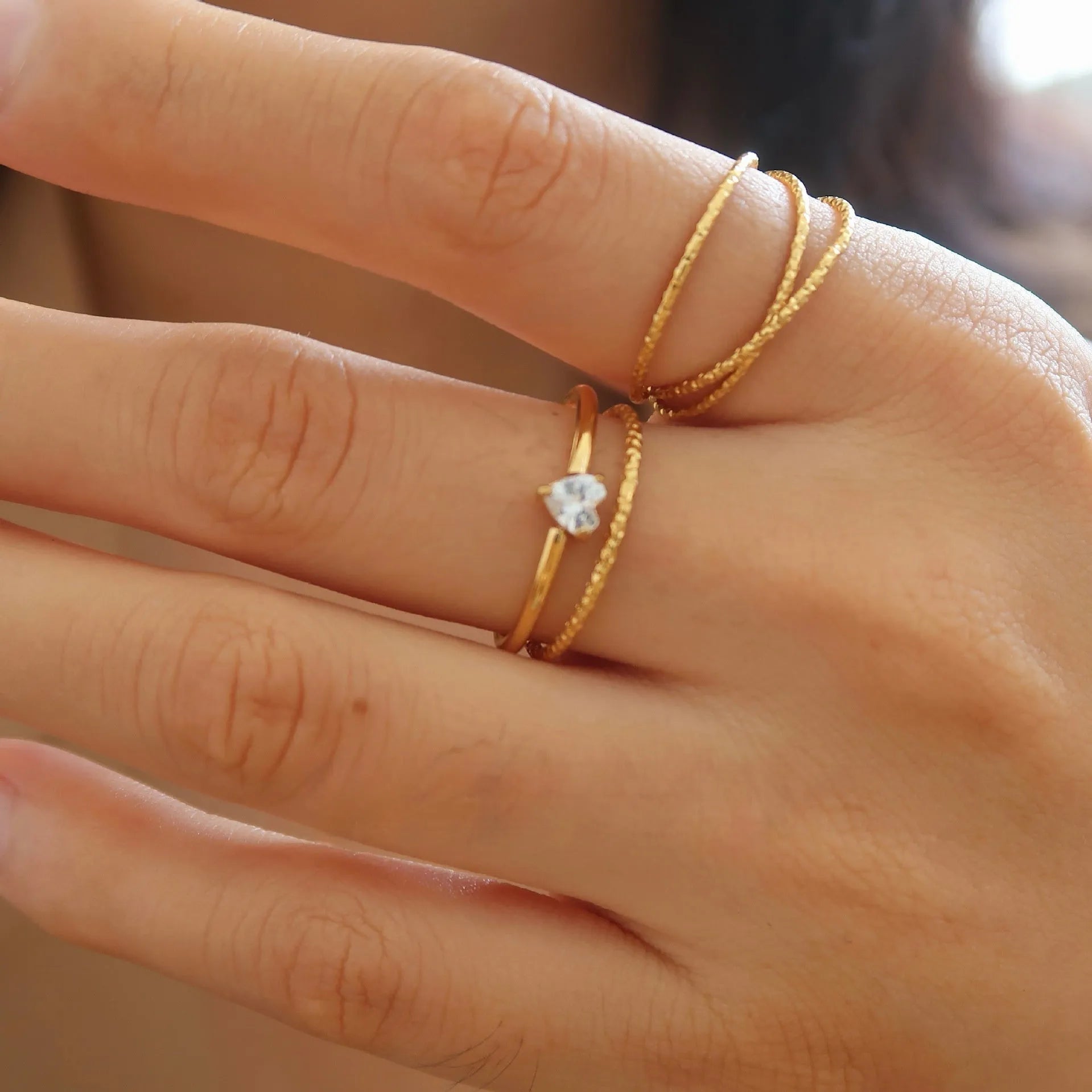Gold electroplated stainless steel women's ring with heart design in oval shape on finger