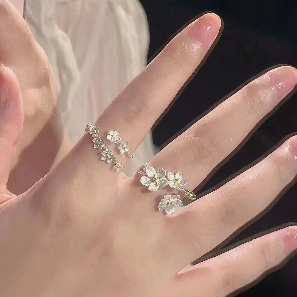 Open silver-tone ring with a 3D jasmine flower and multiple small flowers on the band.