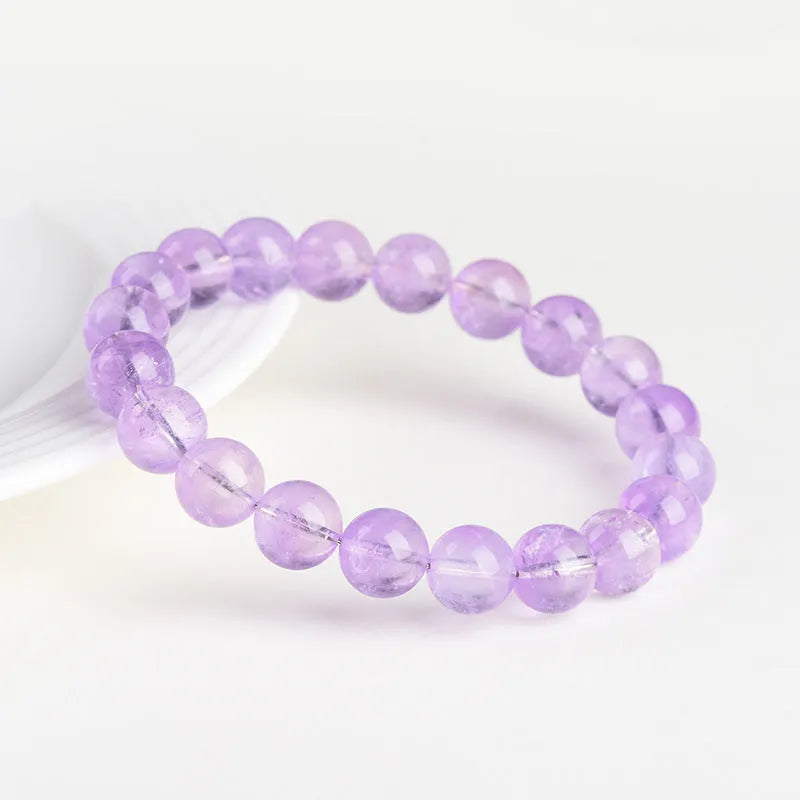 Light purple amethyst crystal bracelet with round beads and water ripple design on a wrist.