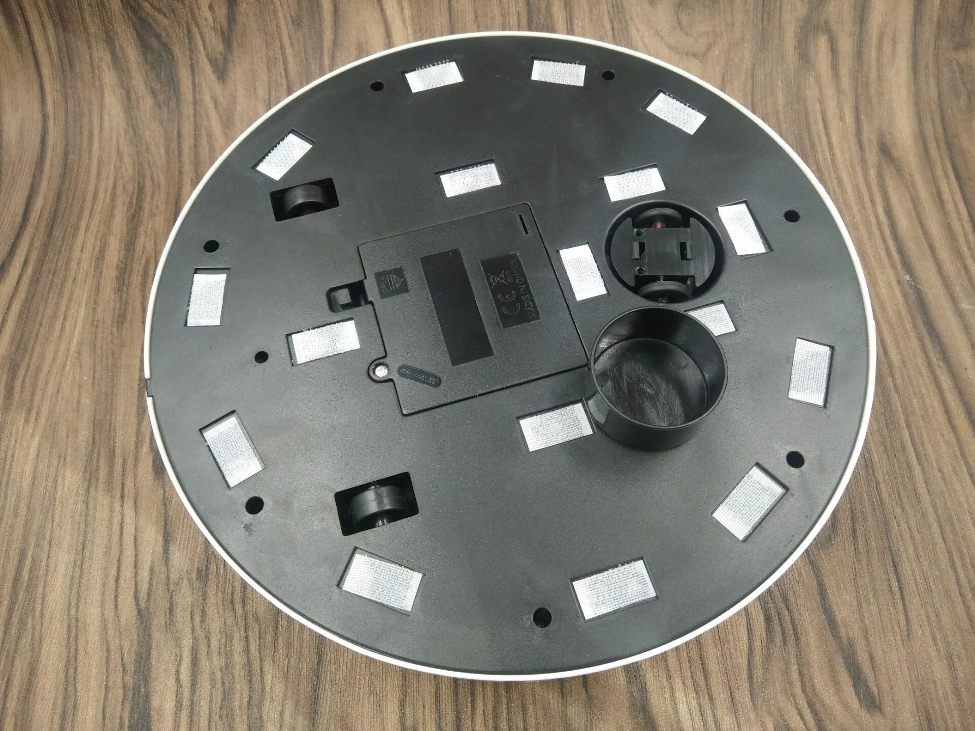 Black or white AC automatic floor sweeping robot on a wooden floor.