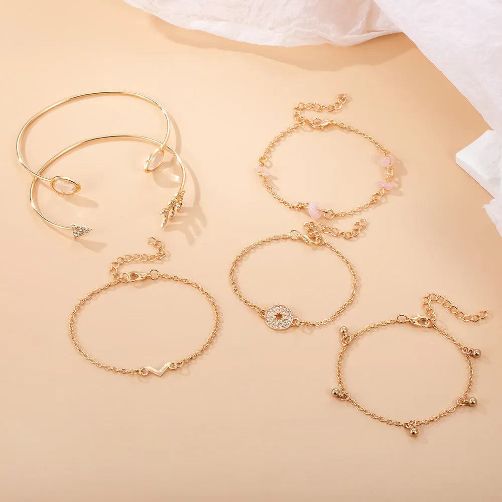 Gold-coloured zinc alloy bracelet set with six charms including arrow, water drop, V, and spot drill designs.
