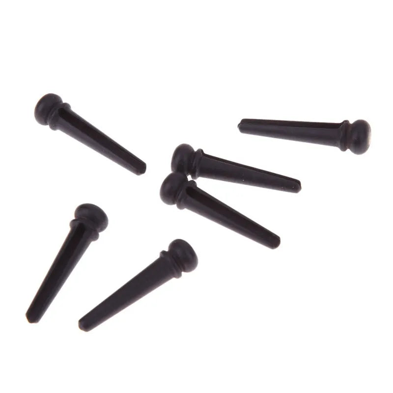 Set of six matt black ebony guitar bridge pins or string nails for acoustic guitar.