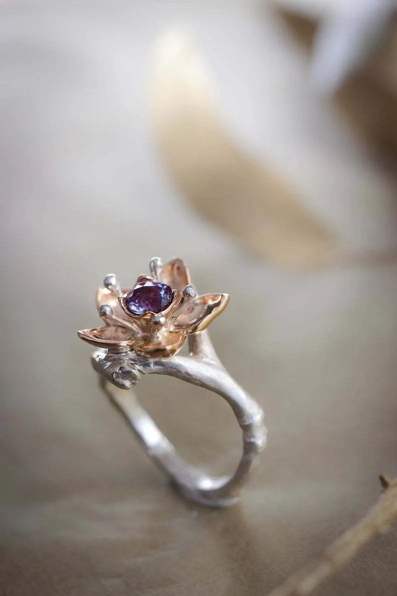 Silver two-tone alloy ring with geometric floral design on a white background.
