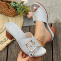 Women's black chunky heel slippers with a silver metal buckle and rubber sole on a light background.