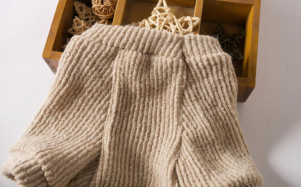 Brown knitted dog sweater on a small white dog, showing a casual pullover style.