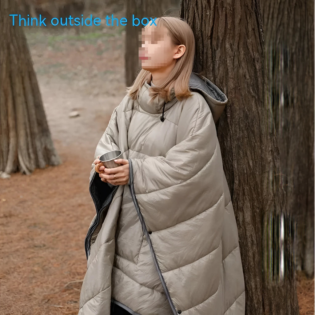 Adult wearing grey nylon cloak sleeping bag as wearable camping blanket outdoors