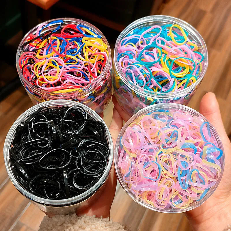 Multi-colour TPU baby hair ties in a reusable plastic storage container.