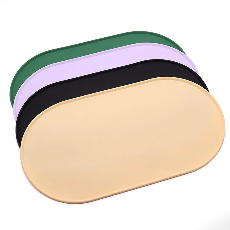 Green silicone placemat for cat bowls on a wooden floor.