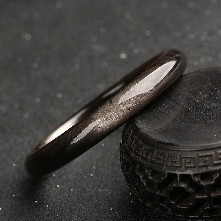 Obsidian cat's eye ethnic bracelet with geometric design on wrist, showing alloy and crystal construction.