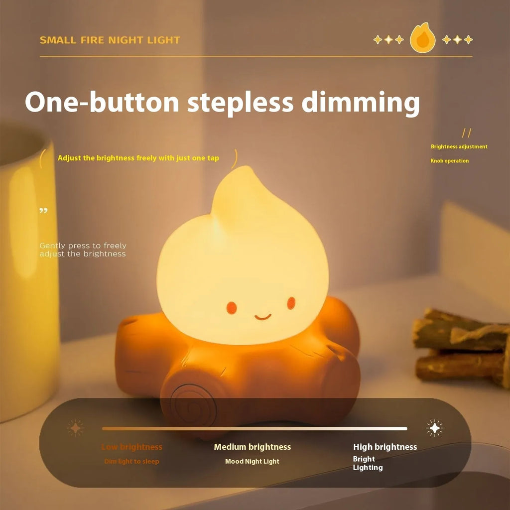 Small cartoon silicone fire pile night light with yellow LED glow and ABS shade on wooden surface.