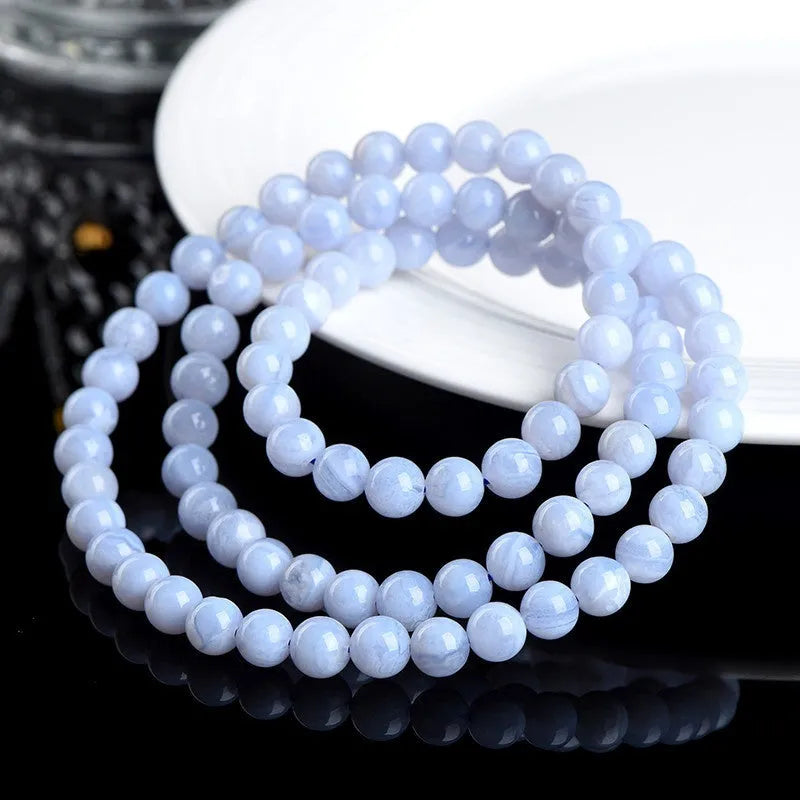 Close-up of a blue agate beaded bracelet with multi-circle pattern and scattered striped beads on a wrist.