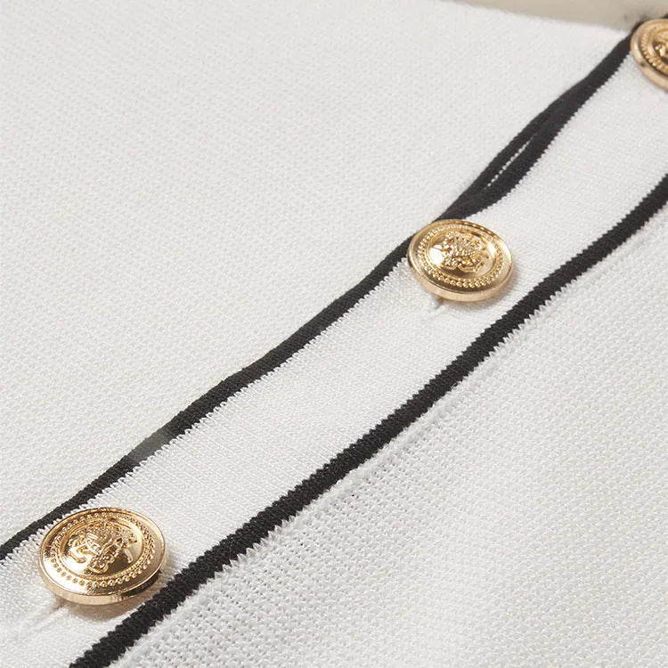 White women's short sleeve cardigan with dark contrast lapels on a hanger.