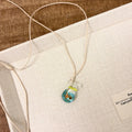 Women's joker pendant necklace with coloured glaze ornament on a cotton and linen clavicle chain.