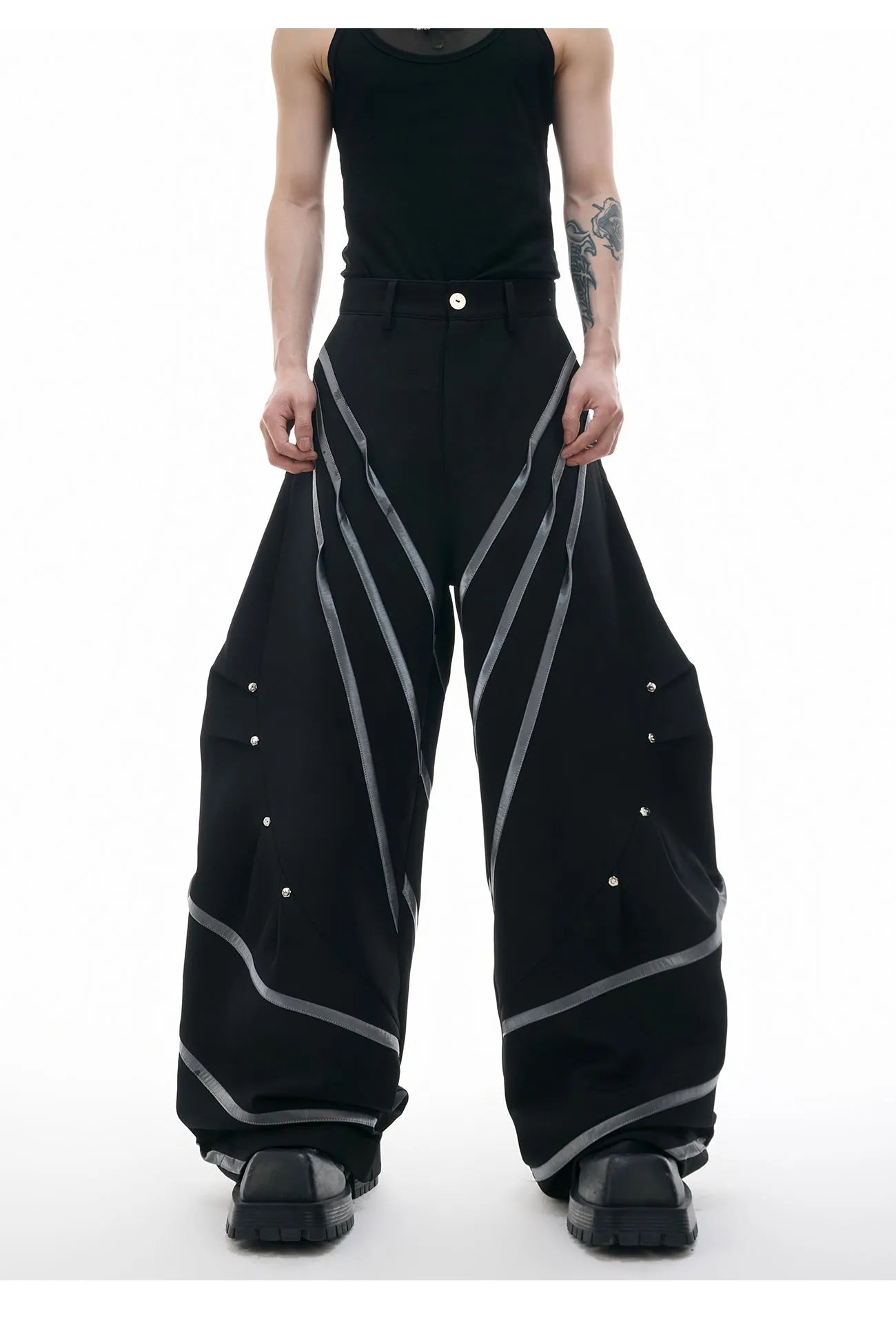Men's black trousers with three-dimensional cutting and metal rivet pleats on a white background.