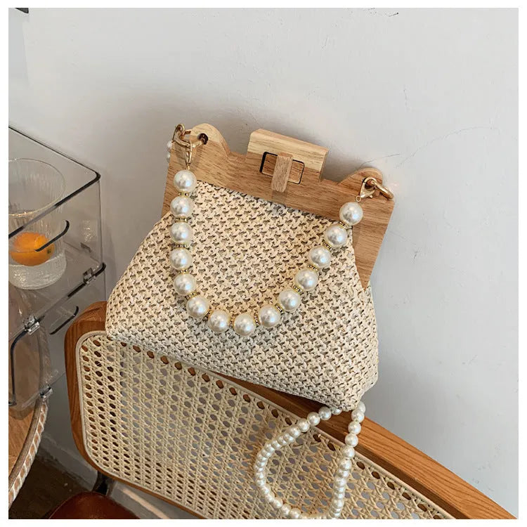 Women's woven straw shoulder bag with pearl chain strap and zippered interior pockets in beige, black, or khaki