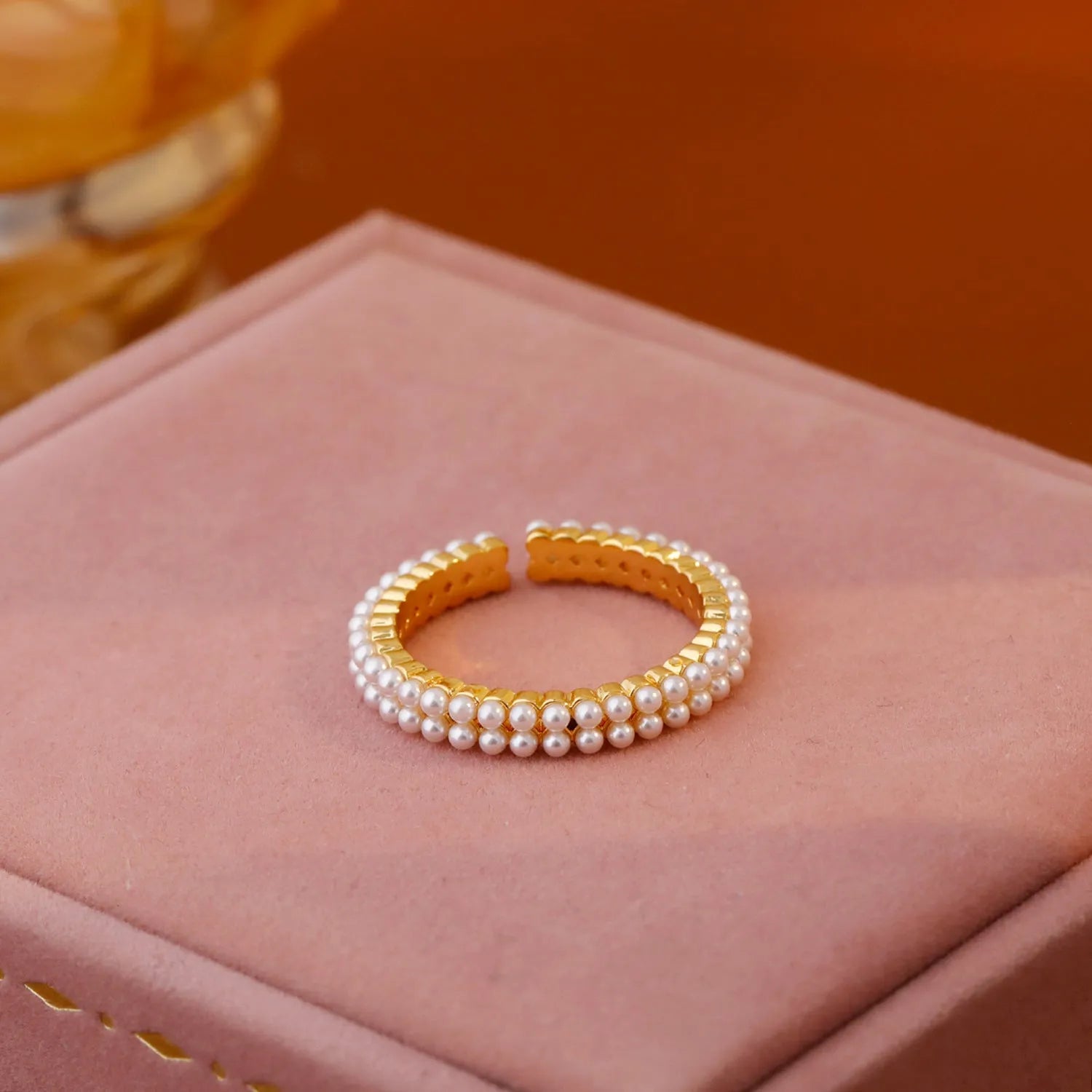 Gold geometric open ring for women with round pearls on a white background.