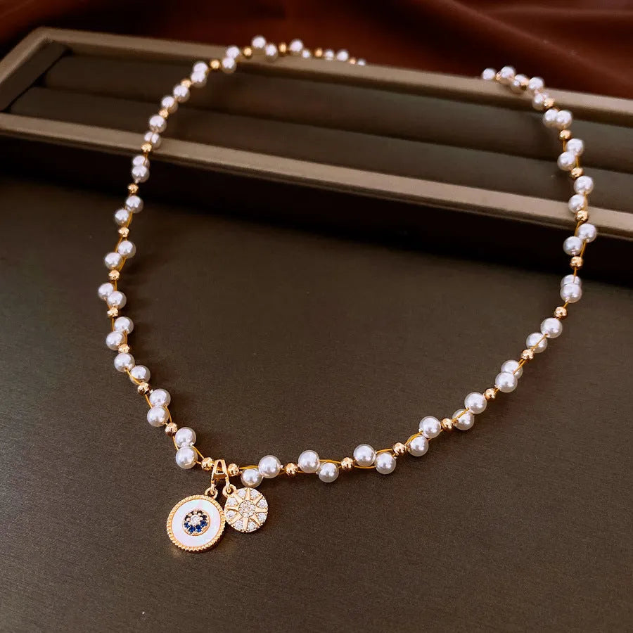 Gold electroplated necklace with zircon and imitation pearl pendant on an adjustable clavicle chain.