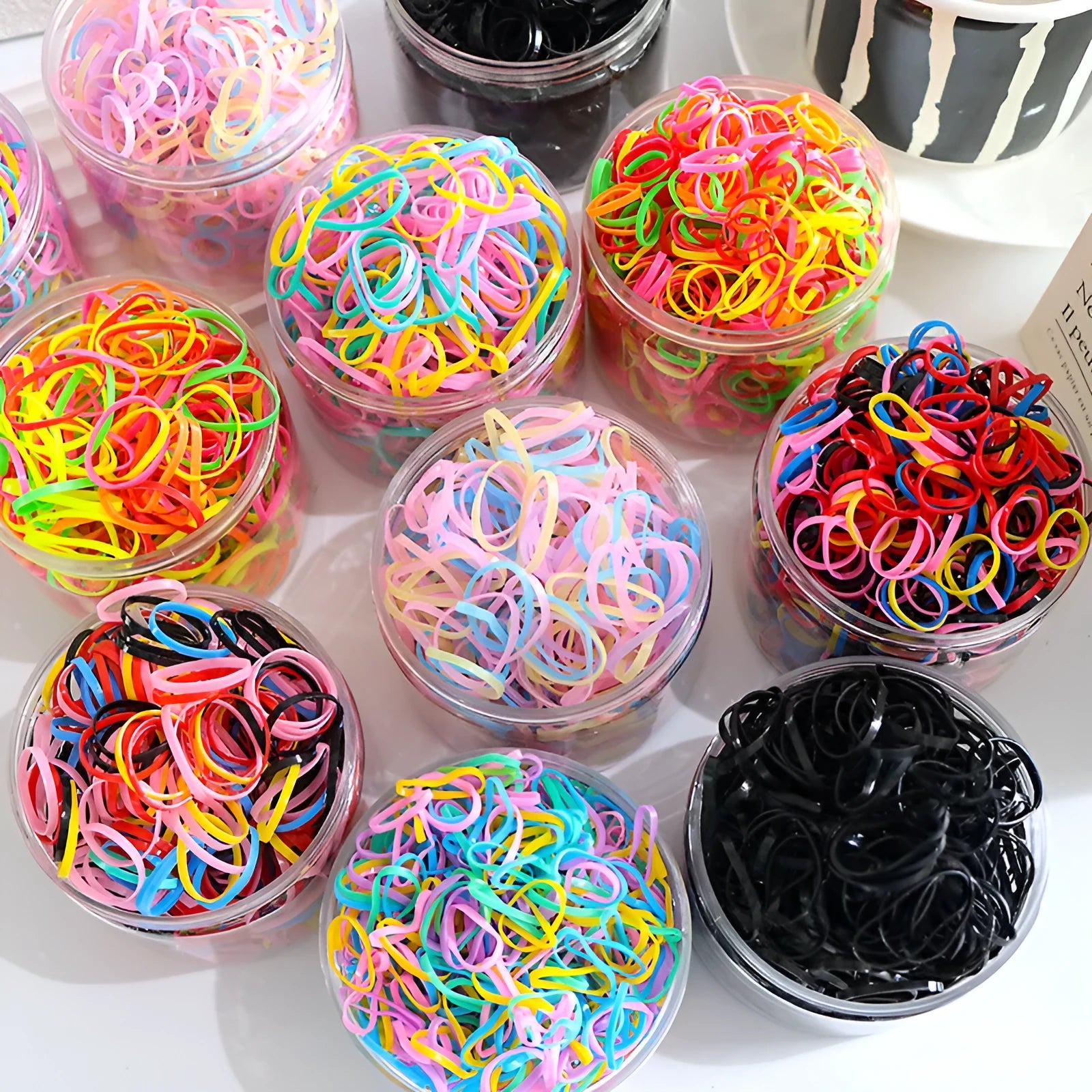 Multi-colour TPU baby hair ties in a reusable plastic storage container.