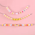 Colourful plastic bead pet necklace for a cat or dog in peach, rainbow, or small flower pattern.