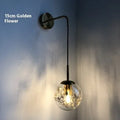 Modern glass wall lamp with golden flower pattern, 20cm size, emitting warm LED light.