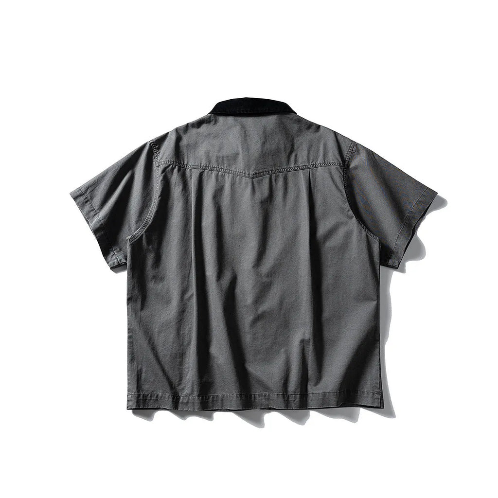 Loose grey short sleeve overalls shirt with cardigan front on a hanger.