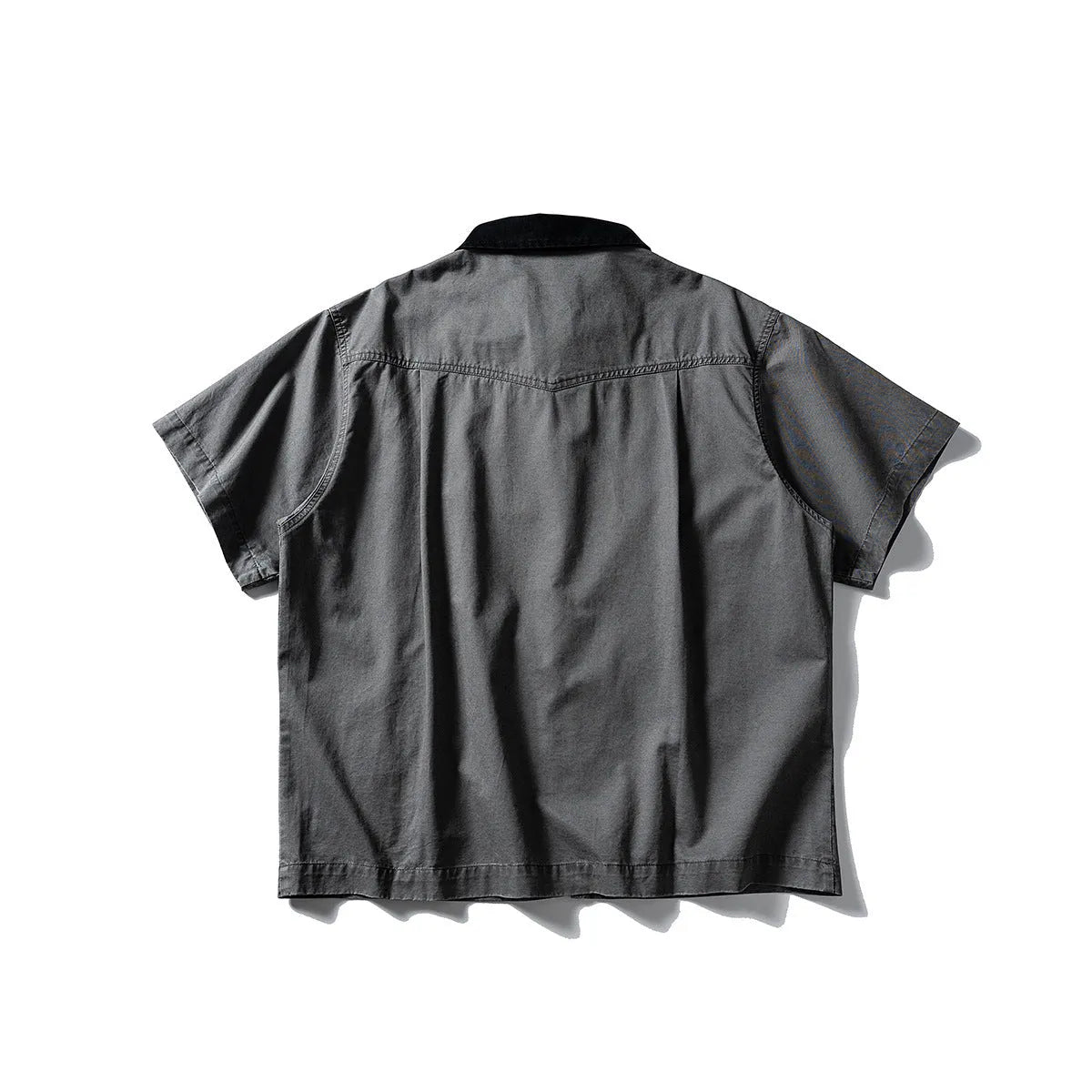 Loose grey short sleeve overalls shirt with cardigan front on a hanger.