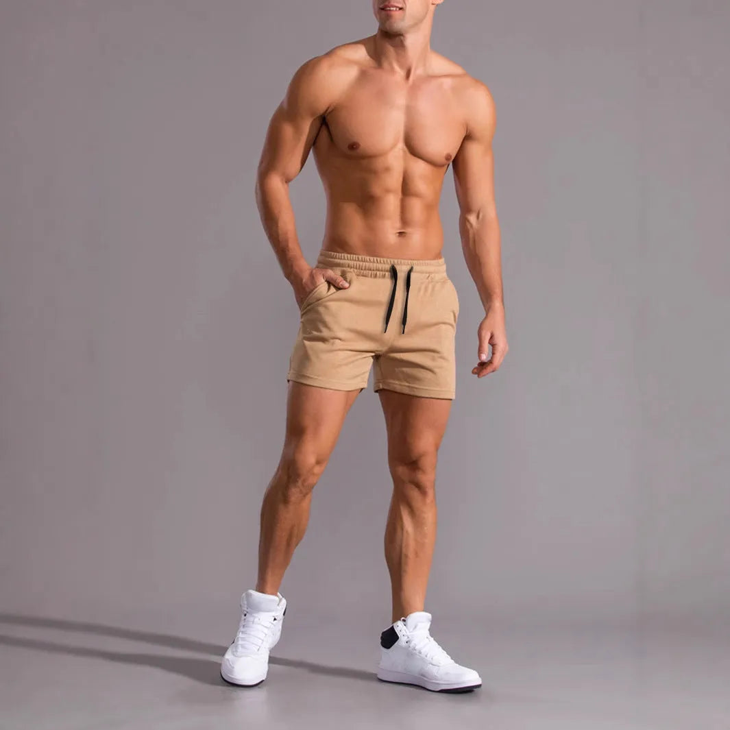 Set of three solid colour men's drawstring shorts in black, khaki, and light brown laid flat.