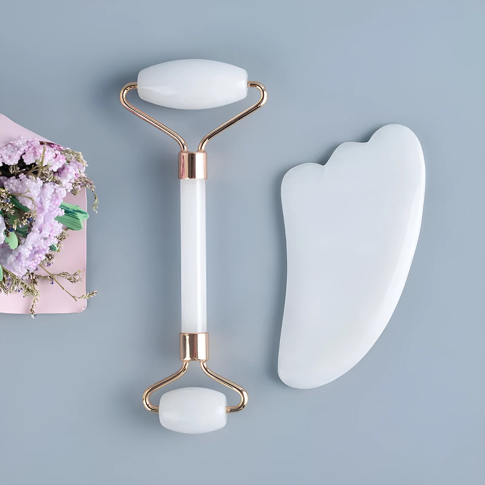 White jade double-headed facial roller and gua sha scraping board set on a neutral background.