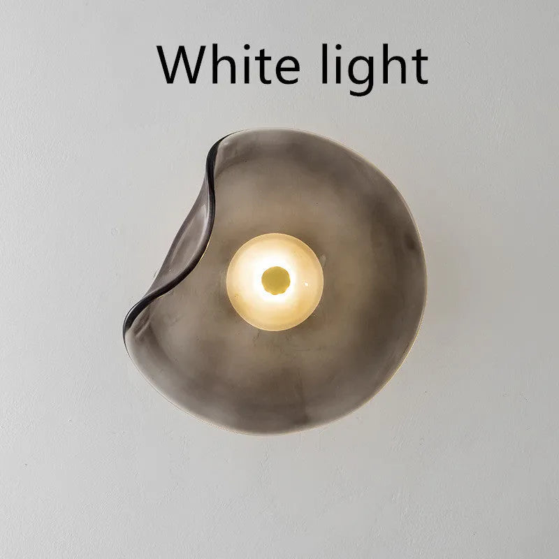 Round decorative wall lamp with glass shade in choice of cognac, light purple, or smoky grey finishes for bedroom lighting