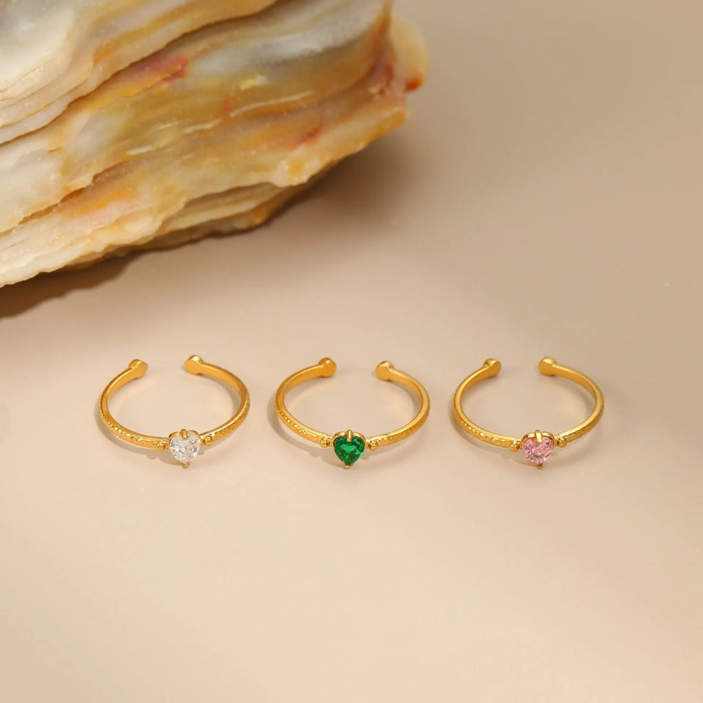 Open ended stainless steel ring with a geometric zirconium love heart inlay in green, pink, or white.