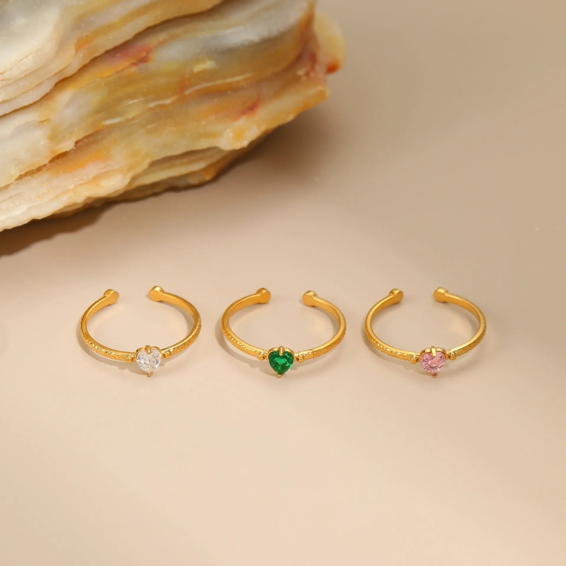 Open ended stainless steel ring with a geometric zirconium love heart inlay in green, pink, or white.