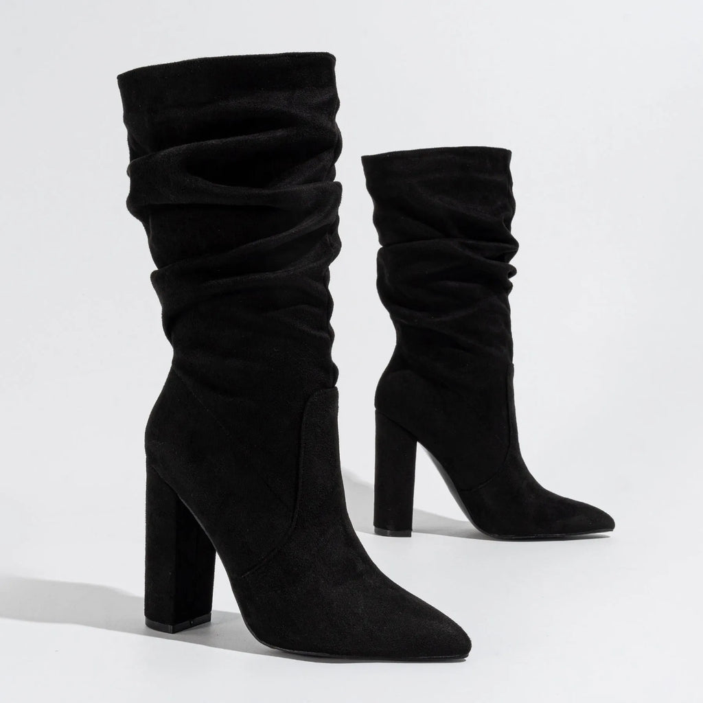 Women's black suede pointed-toe boots with a chunky high heel on a neutral background.