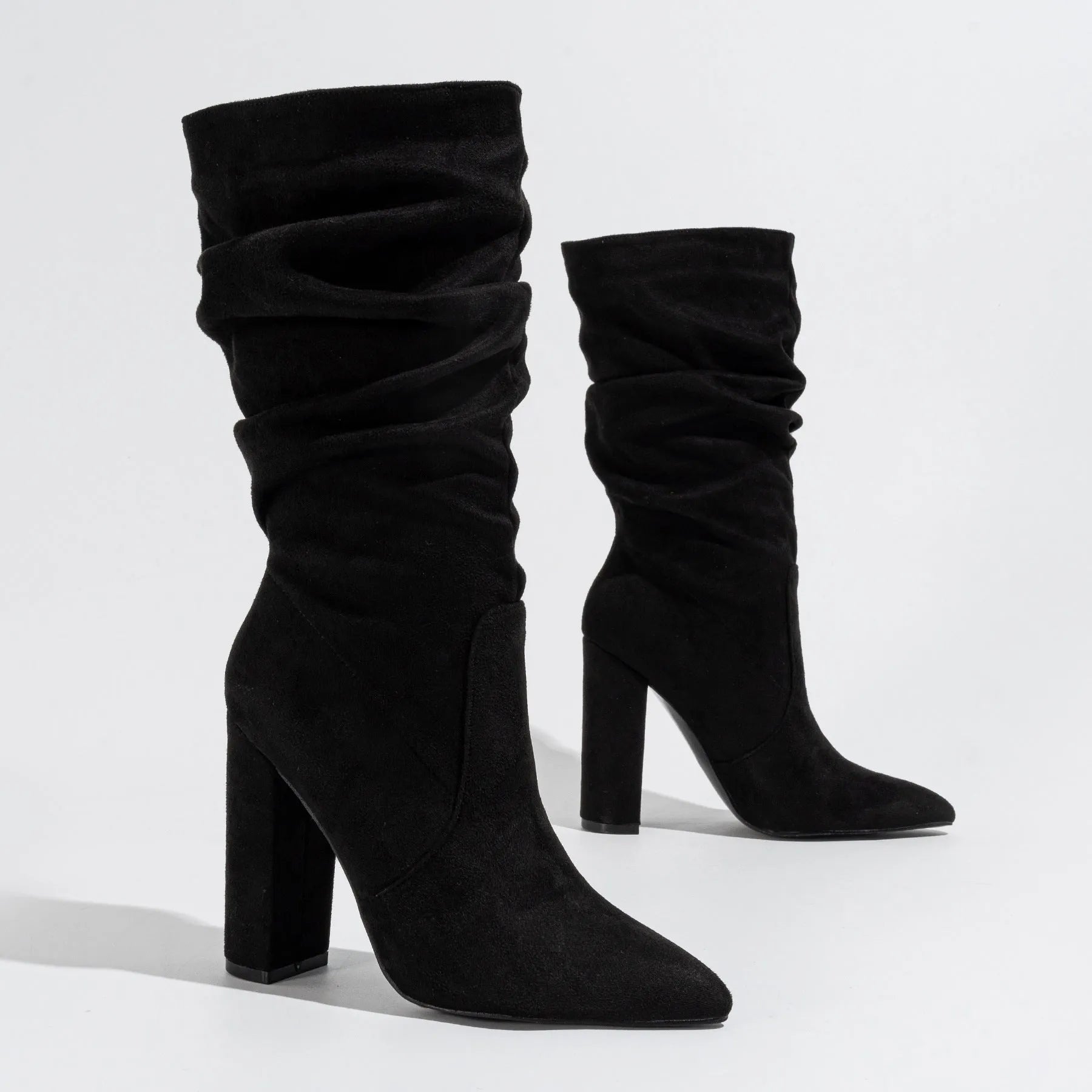 Women's black suede pointed-toe boots with a chunky high heel on a neutral background.
