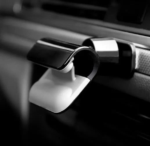 Black gravity car phone holder with adhesive mount, showing 360-degree rotation mechanism.