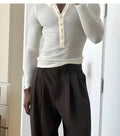Man wearing a cream-coloured ribbed long-sleeve henley top with button-front detail.