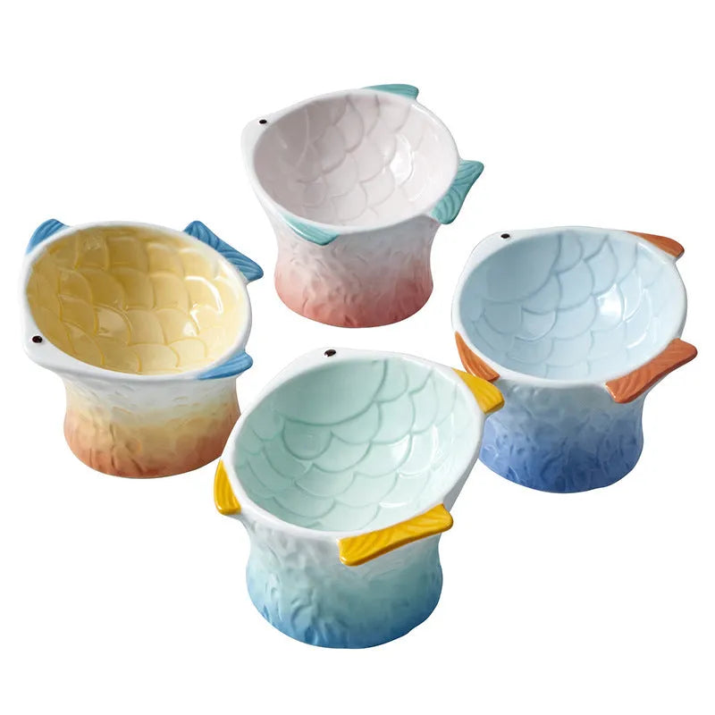 Blue fish-shaped ceramic cat bowl with tilted design on a wooden surface.