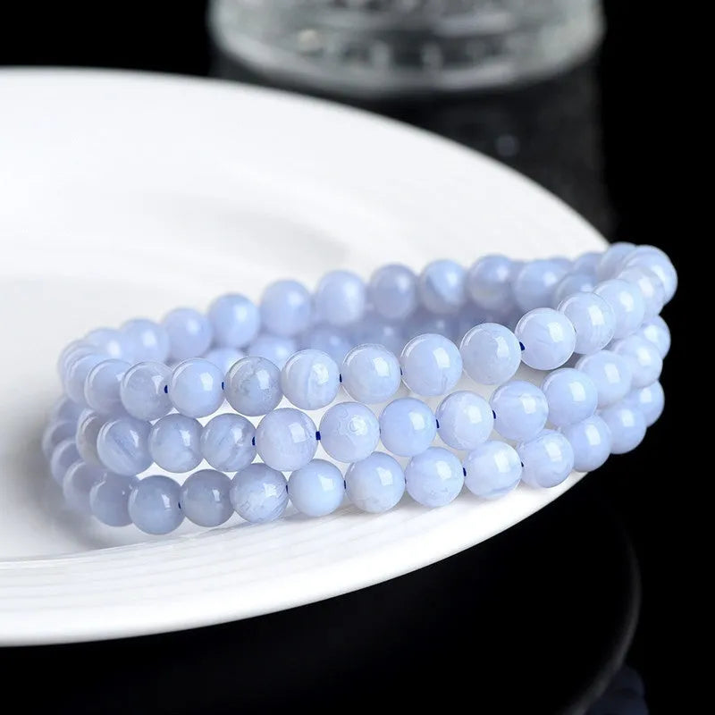 Close-up of a blue agate beaded bracelet with multi-circle pattern and scattered striped beads on a wrist.