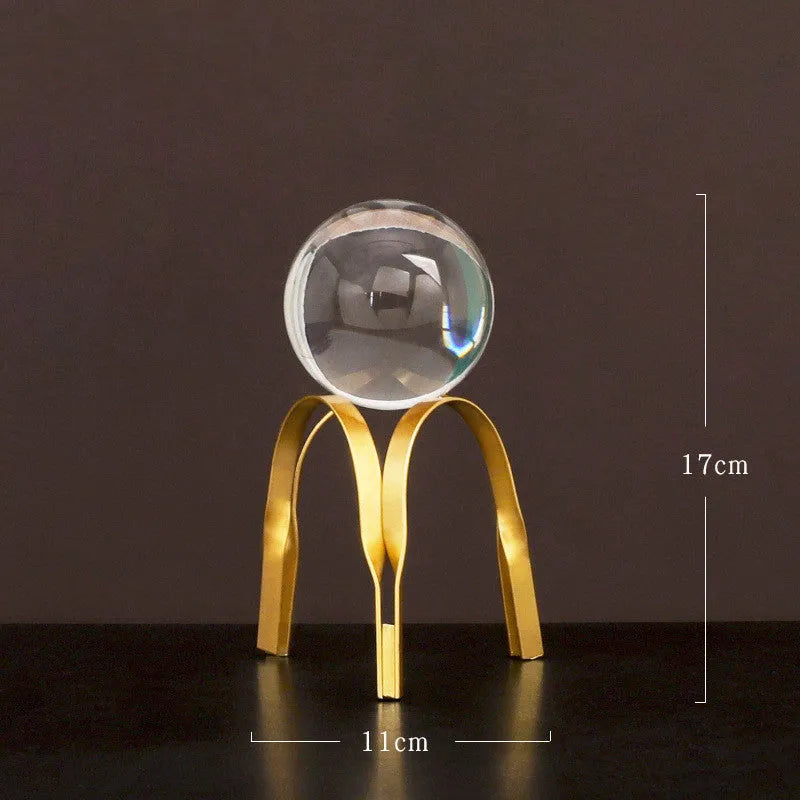 Nordic gold metal crystal ball ornament on a table, abstract shape with clear glass ball