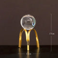Nordic gold metal crystal ball ornament on a table, abstract shape with clear glass ball