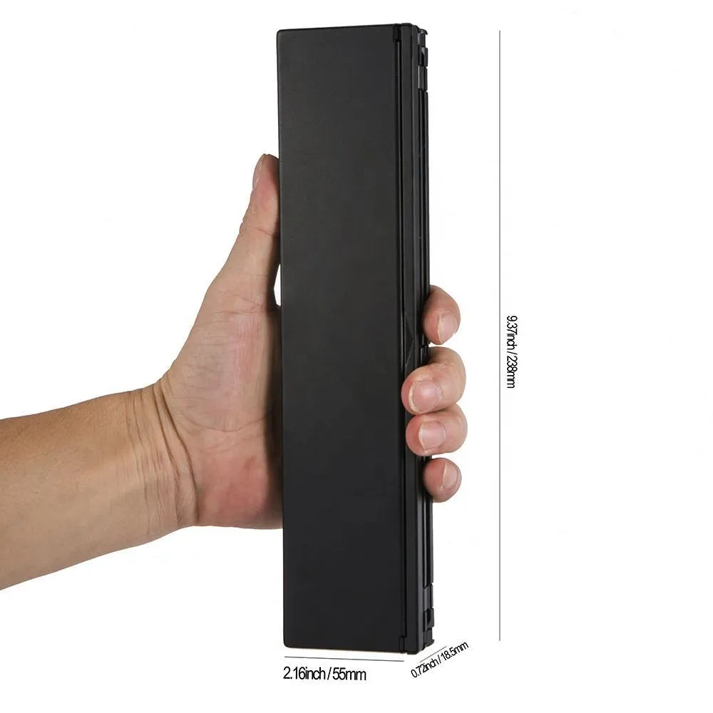 Black foldable ultra-thin wireless Bluetooth keyboard for tablets shown open next to a mobile phone.