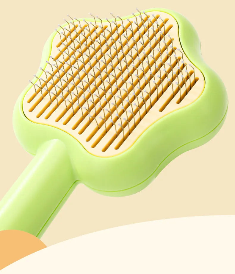 Green and yellow self-cleaning cat comb with stainless steel needles for pet grooming.