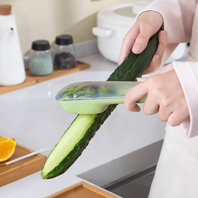 Green vegetable and fruit peeler with a storage tube and stainless steel blade on a kitchen counter.