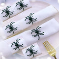 Six black alloy spider-shaped napkin rings for Halloween table settings.