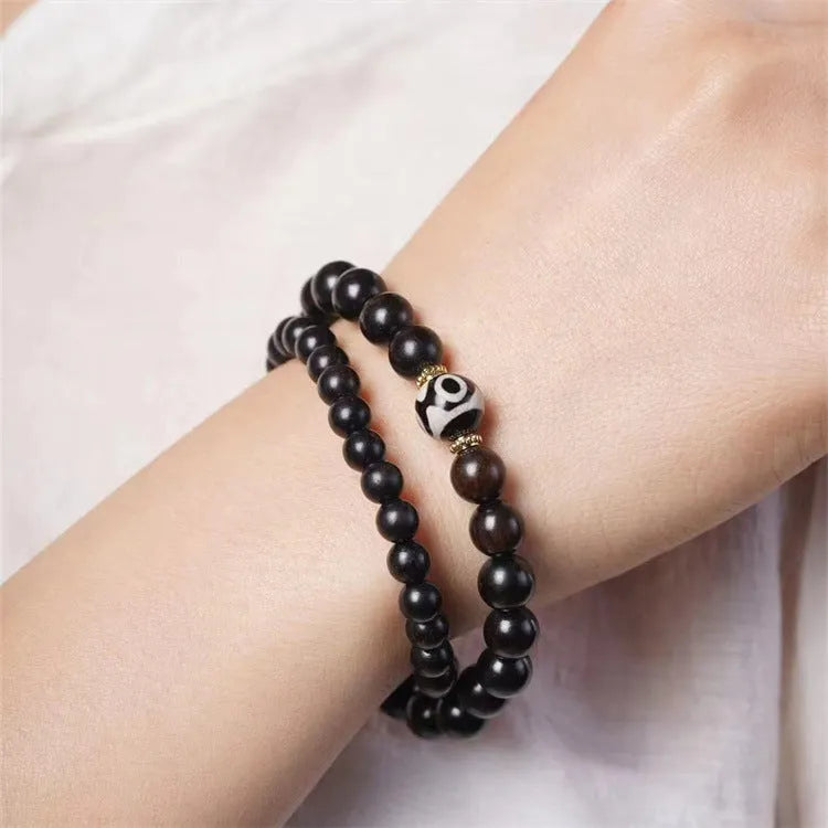 Ebony beaded bracelet with two-circle Tibetan-inspired design on wrist