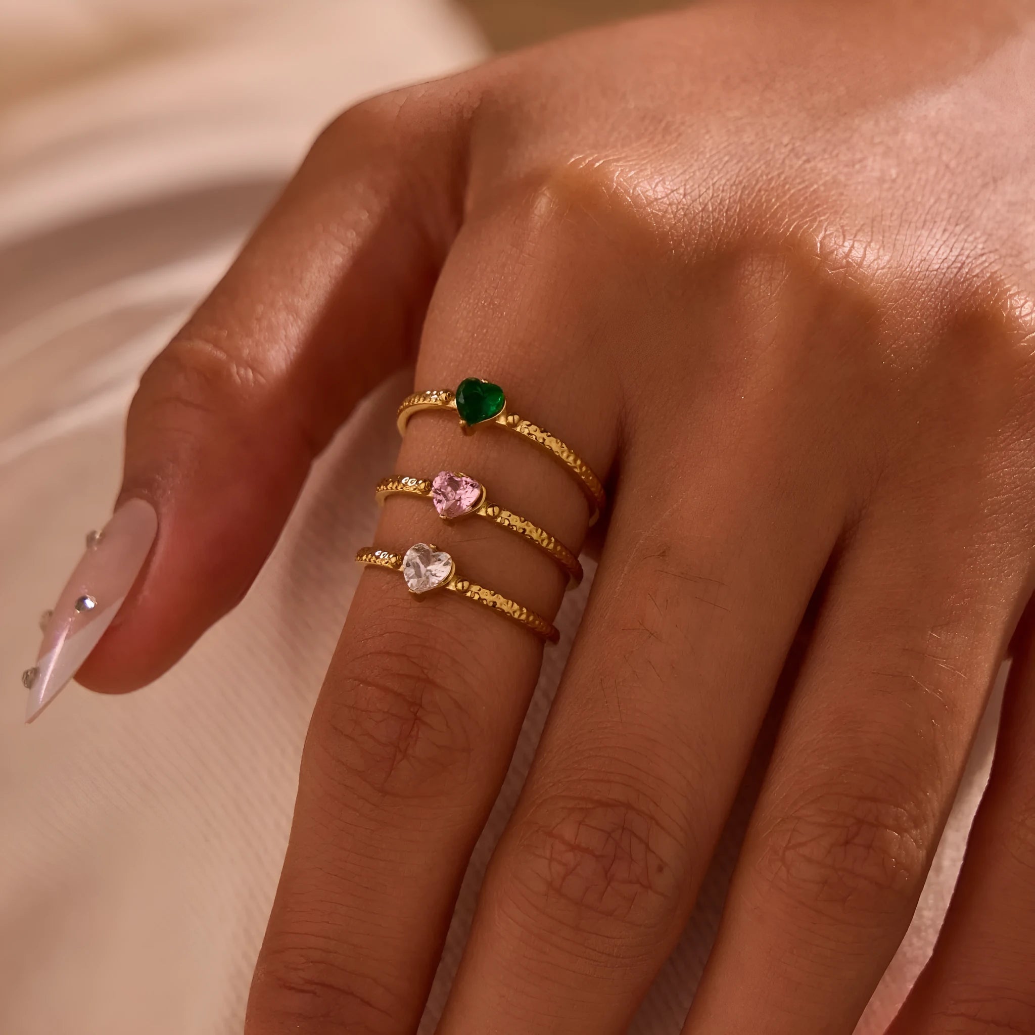 Open ended stainless steel ring with a geometric zirconium love heart inlay in green, pink, or white.