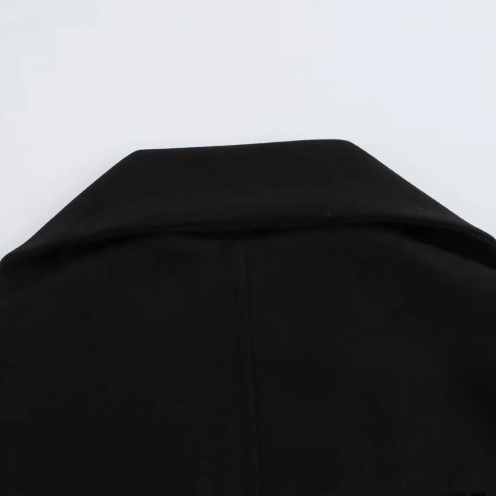 Women's long black overcoat with grey artificial fur collar, showing longline silhouette and pocket detail.