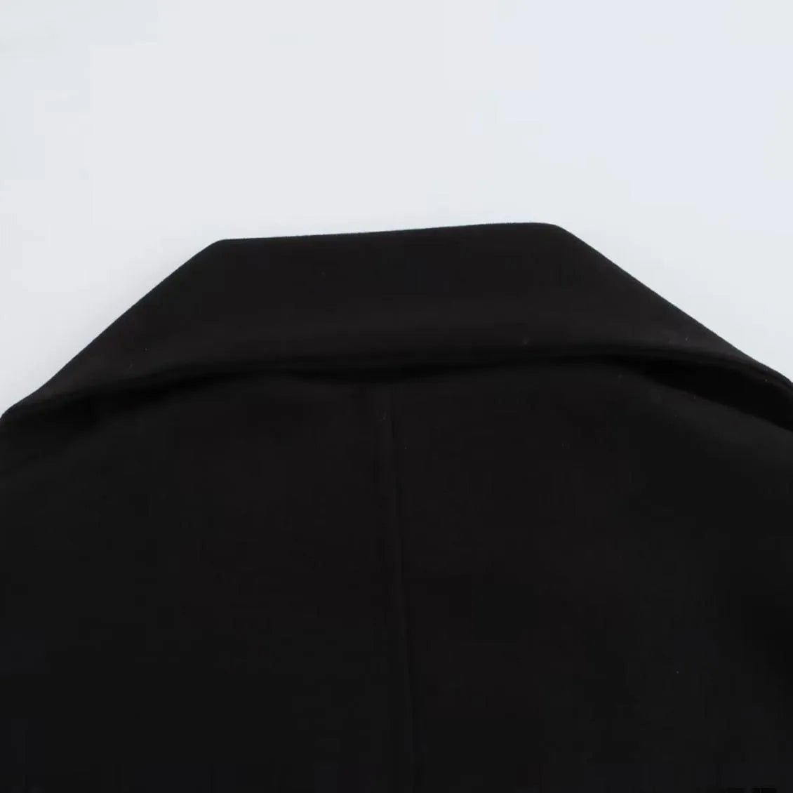 Women's long black overcoat with grey artificial fur collar, showing longline silhouette and pocket detail.