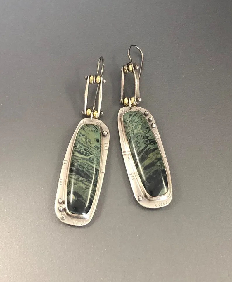 Geometric alloy earrings with a white and grey marble pattern on a simple background.