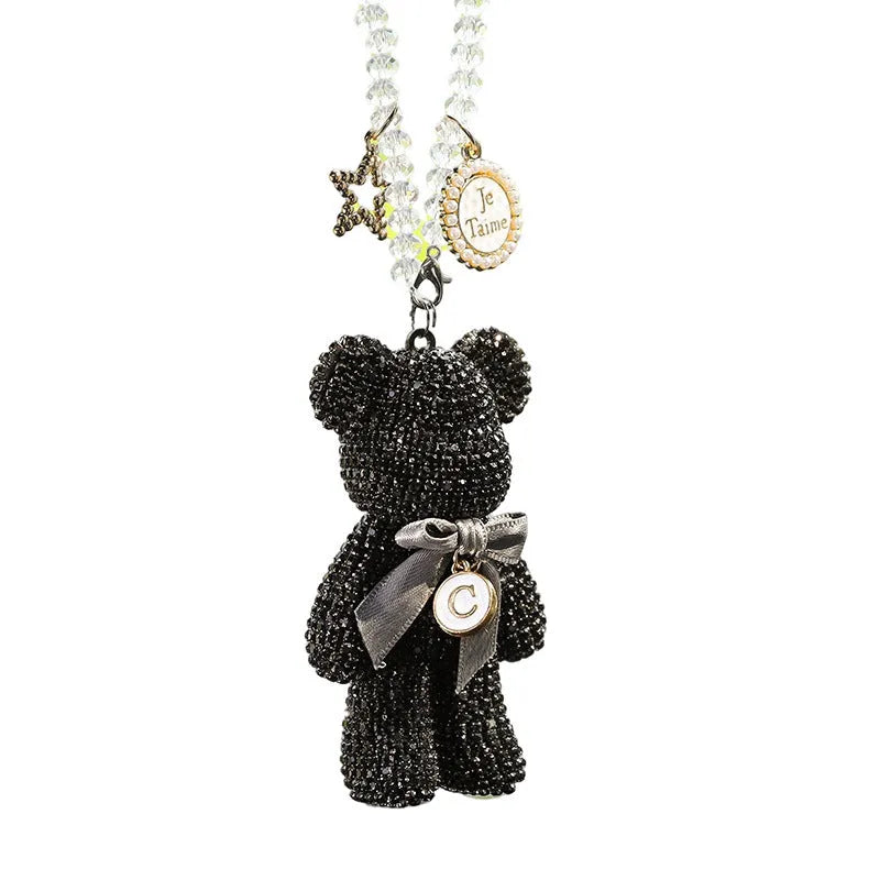 Close-up of a crystal rhinestone Violent Bear ornament on a car rearview mirror.